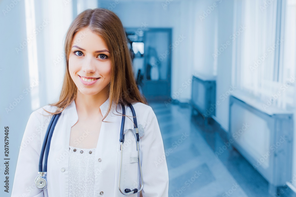 Confident female doctor sitting at office desk and smiling at camera, health care and prevention concept Confident female doctor sitting at office desk and smiling at camera, health care and prevention concept
