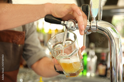 Bartender pouring fresh cold beer from tap, closeup