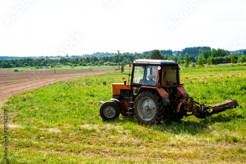  Tractor on the field mows the grass