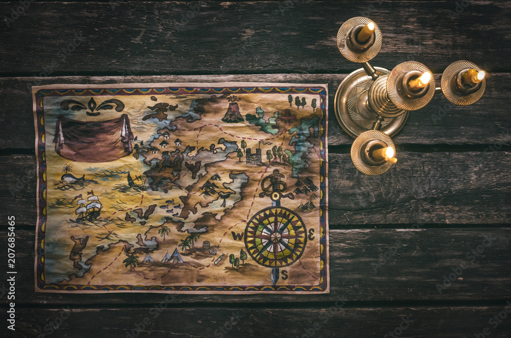 Fototapeta premium Pirate treasure map and burning candle on aged wooden table background. Treasure hunt concept. Sea travel.