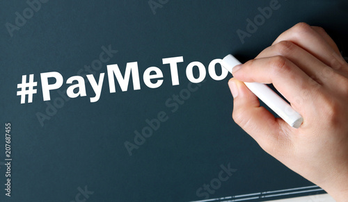 The hand writing text #PayMeToo in white chalk. photo