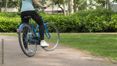 Girl rides bicycle in a city park close up