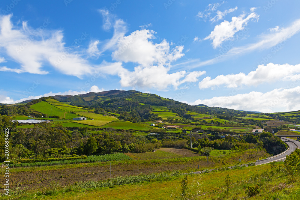 Picturesque landscape of Sao Miguel Island on Azores, Portugal. Hills with sweeping vistas, pastures and forests of the largest volcanic island under blue skies.