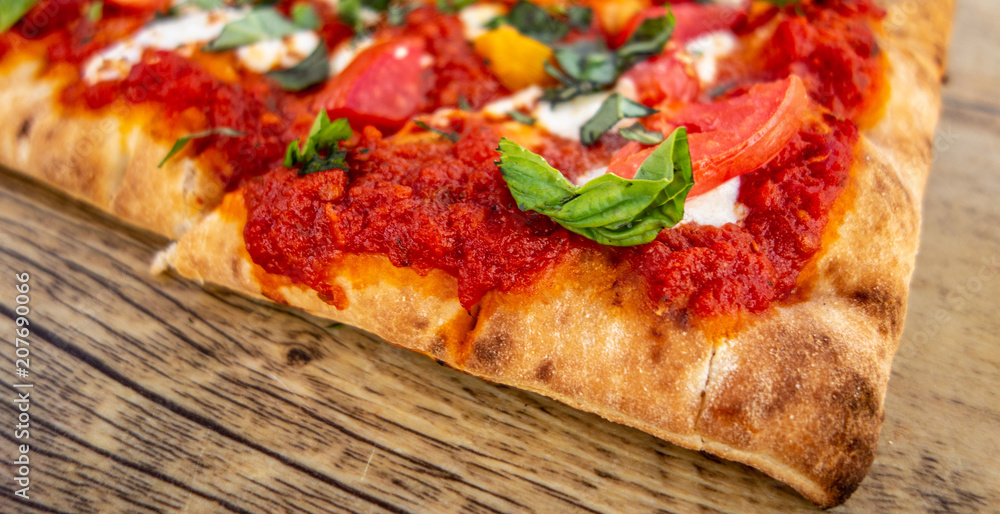 Slice of Classic Margherita Flatbread: Tomato Base, Fresh Mozzarella, Sliced Tomatoes, Basil on old rustic wood board, close up, wide photo Slice of Classic Margherita Flatbread: Tomato Base, Fresh Mozzarella, Sliced Tomatoes, Basil on old rustic wood board, close up, wide photo