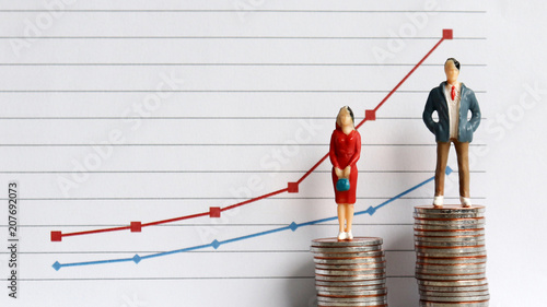 Photos Miniature people standing on a pile of coins in front of a graph