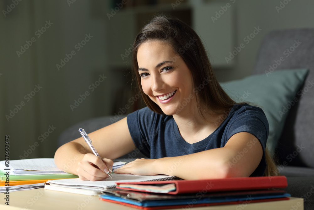 Happy student studying late hours looking at you Happy student studying late hours looking at you