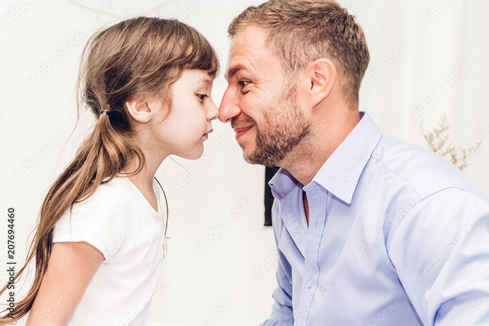 Little girl with dad smiling and touching nose together at home.Love of family and father day concept Little girl with dad smiling and touching nose together at home.Love of family and father day concept