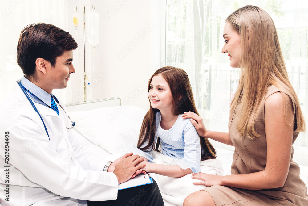 Doctor holding hand little girl with care on doctors table in hospital.healthcare and medicine Doctor holding hand little girl with care on doctors table in hospital.healthcare and medicine