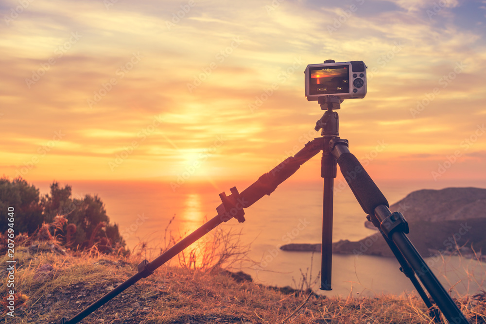Camera taking picture film of sunrise over sea surface