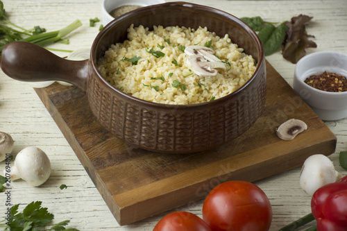 Bulgur in plate on wooden table. Traditional middle eastern or arab dish. Top view. vegetarian dinner. Bulgur  with vegetables, spices on white background. Flat la photo