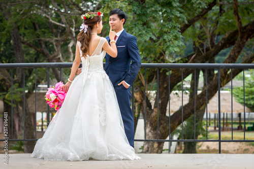 фотографія The bride carries a bouquet of flowers and hands on the groom's mouth