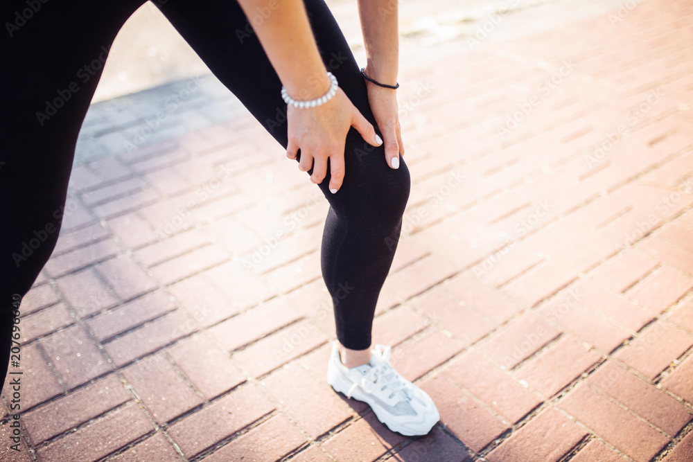 Sporty girl, holding on to injured leg, in pain, can be used for advertising, text insertion Sporty girl, holding on to injured leg, in pain, can be used for advertising, text insertion