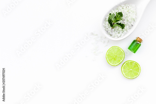 Natural organic cosmetics with lemon or lime. Citrus slices  aromatic spa salt  mint for deoration  bottle with oil on white background top view copy space