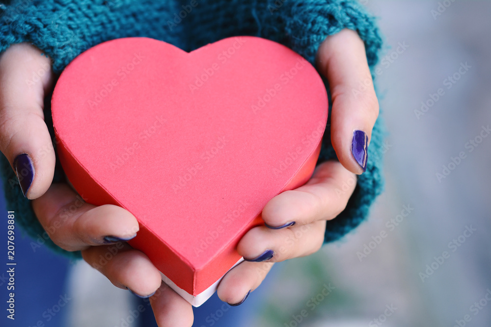 Female hands holding heart shaped gift box. Female hands holding heart shaped gift box.