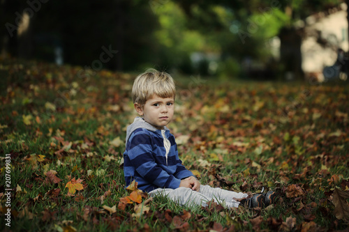 Little boy, playing in the rain in autumn park, leaves around him