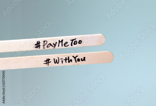 #PayMeToo as a new campaign to close the wage gap between men and women. A wooden stick with #PayMeToo on it and a wooden stick with #WithYou. photo