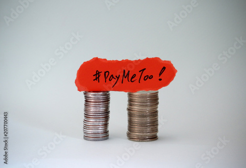 #PayMeToo as a new movement. #PayMeToo written with a torn paper on two piles of coins. photo