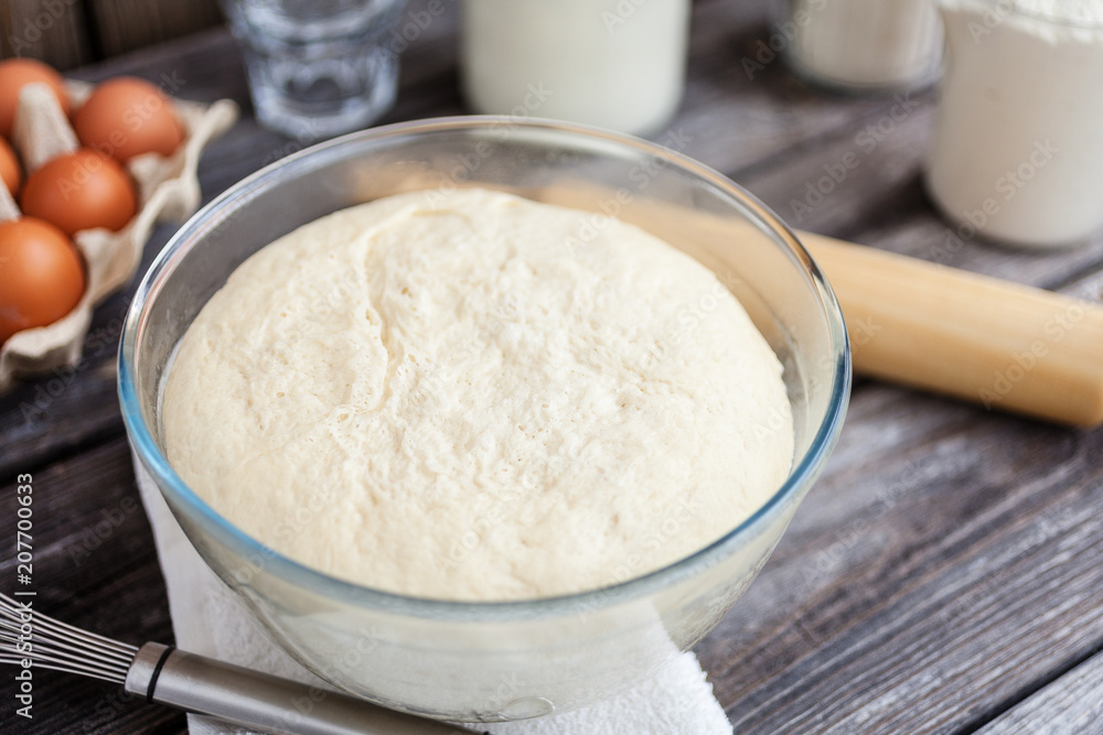 Fresh raw dough ready for baking on rustic wooden background