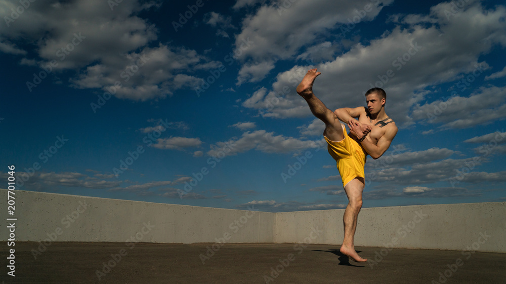 Tricking on street. Martial arts. Man makes roundhouse kick barefoot
