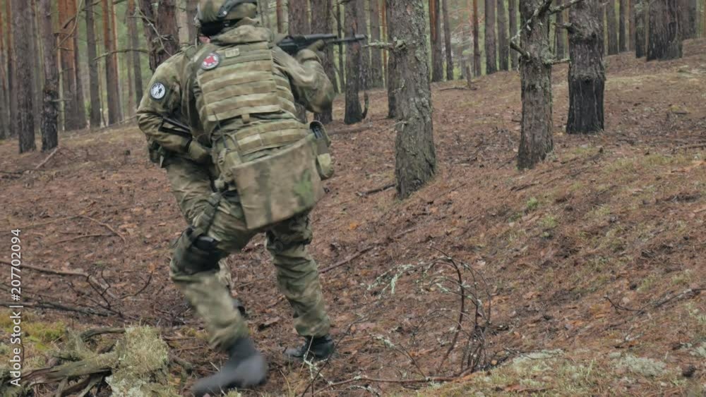 Soldiers in camouflage with combat weapons are being fired in the shelter of the forest, the military concept Soldiers in camouflage with combat weapons are being fired in the shelter of the forest, the military concept
