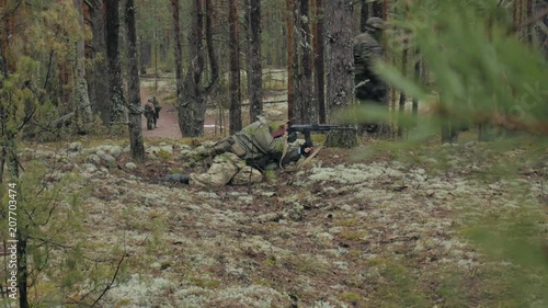 Soldiers in camouflage with combat weapons are being fired in the shelter of the forest, the military concept photo