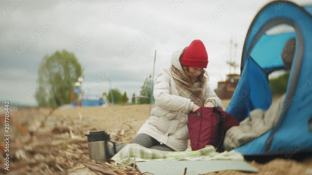 Tourist tent on the river bank. two girl sits near the tent eating and drinking looks at the river. Tourist tent on the river bank. two girl sits near the tent eating and drinking looks at the river.