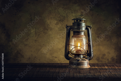 kerosene lamp oil lantern burning with glow soft light on aged wood floor photo