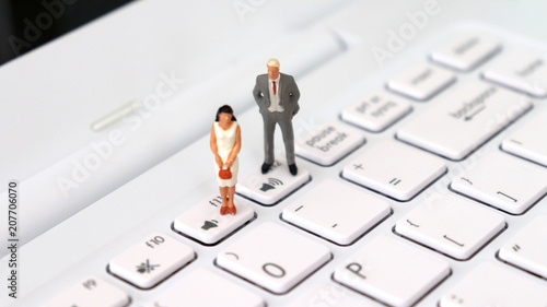 Photography A miniature man and a miniature woman standing on a different volume keyboard