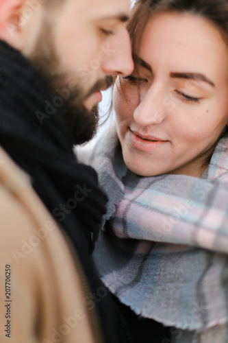 Close up faces of caucasian charming woman and man hugging and wearing scarf. Concept of couple winter photo session. photo