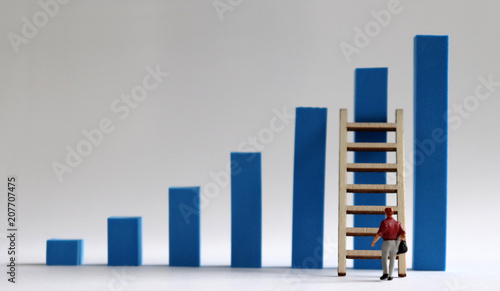 A  miniature  man  walking  to  a  ladder  with  a  blue  bar  graph.