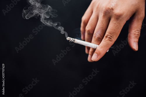 Fingers holding a cigarette, Black background