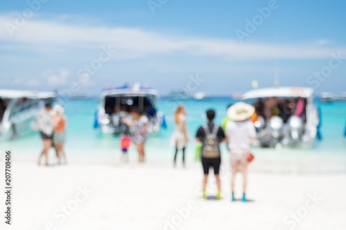 Blurry abstract background of tourist walking on beach and sea shore with mountain at sunny day,summer vacation concept..