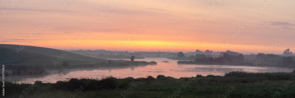 sunrise over a lake surrounded by meadows and fields