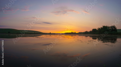 sunrise over a lake surrounded by meadows and fields