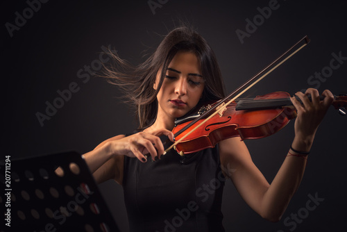 Fototapeta Ładna młoda kobieta bawić się skrzypce nad czarnym tłem