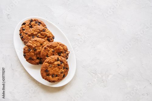 Homemade chocolate chip cookies in a plate on a white stone background. Top view and copy space.