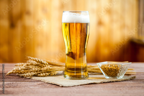 glass of beer with wheat on a wooden table background