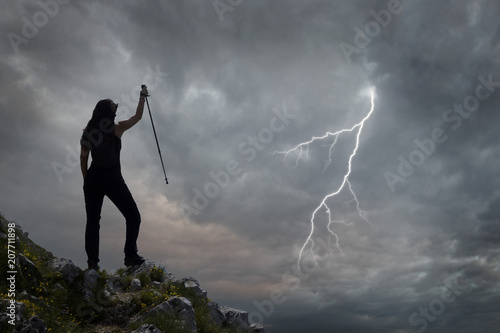 woman hiker on cliff of mountain and lightning