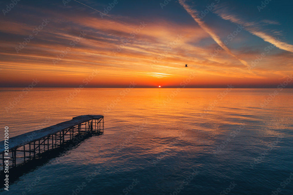 Aerial view over the old broken bridge in the sea, sunrise shot.