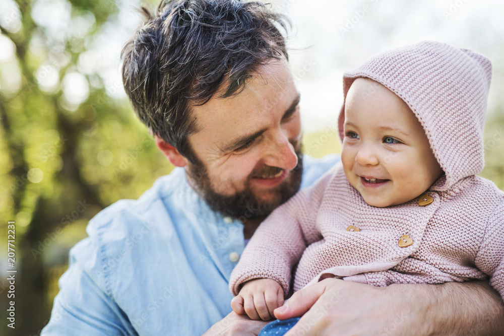 A father with his toddler daughter outside in spring nature.