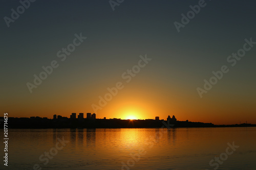 Beautiful sunset over the river with a view of the city, on the horizon.