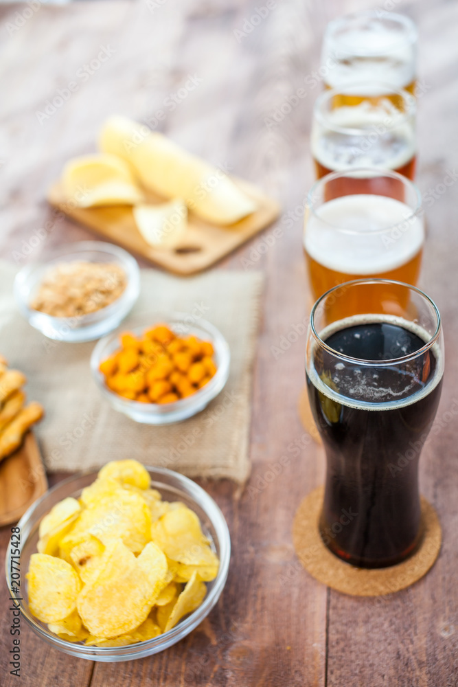 glasses of light and dark beer with assorted snacks on a wooden glasses of light and dark beer with assorted snacks on a wooden