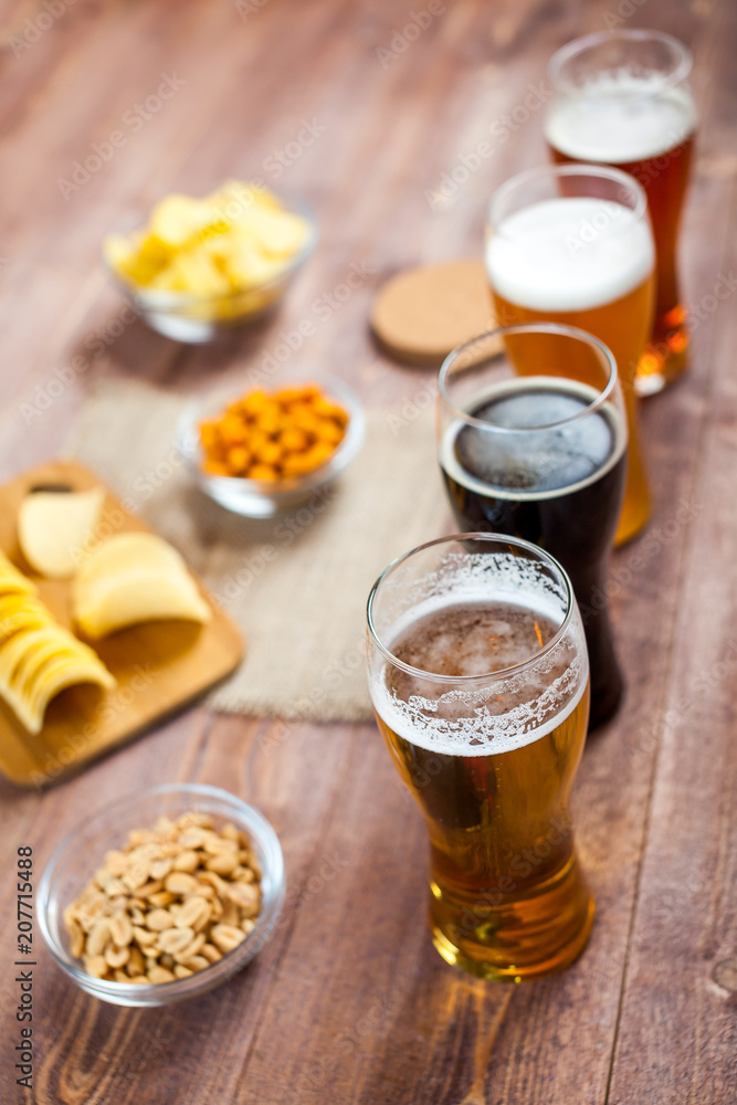 glasses of light and dark beer with assorted snacks on a wooden table background. bachelor party, pub, bar or degustation concept glasses of light and dark beer with assorted snacks on a wooden table background. bachelor party, pub, bar or degustation concept