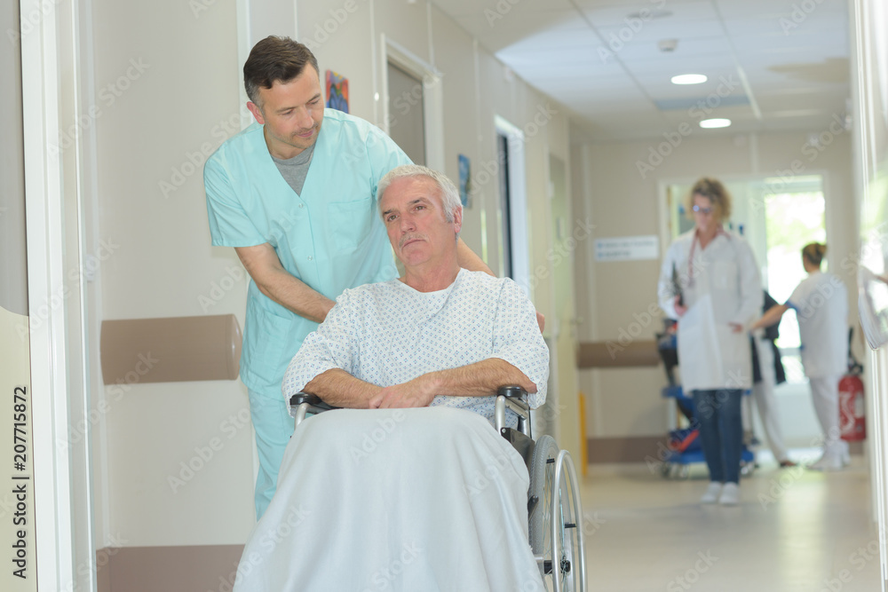 Obraz premium nurse pushing senior patient in wheelchair