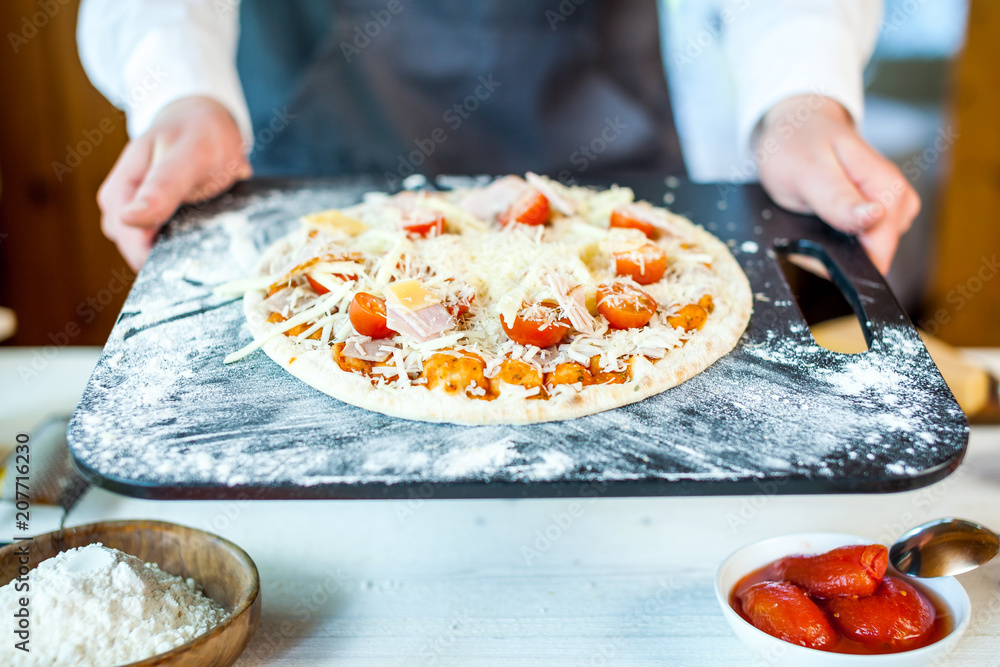 closeup of raw homemade traditional italian pizza in chef hands ready to cook. wallpaper for pizzeria and cooking food concept