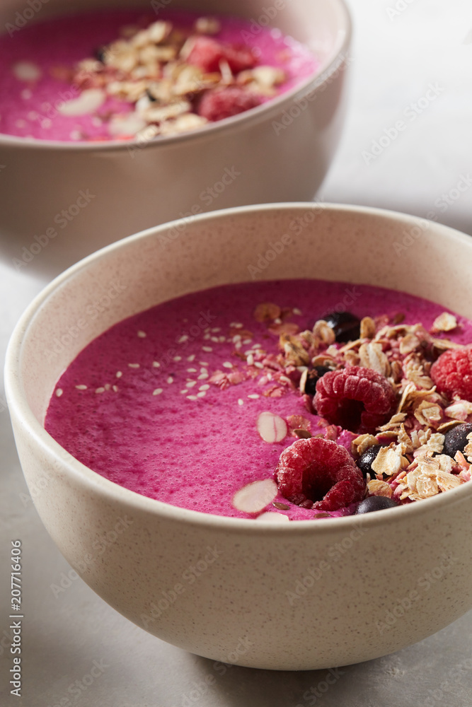 Breakfast smoothie bowl with granola, ice berries and almond on stone background Breakfast smoothie bowl with granola, ice berries and almond on stone background