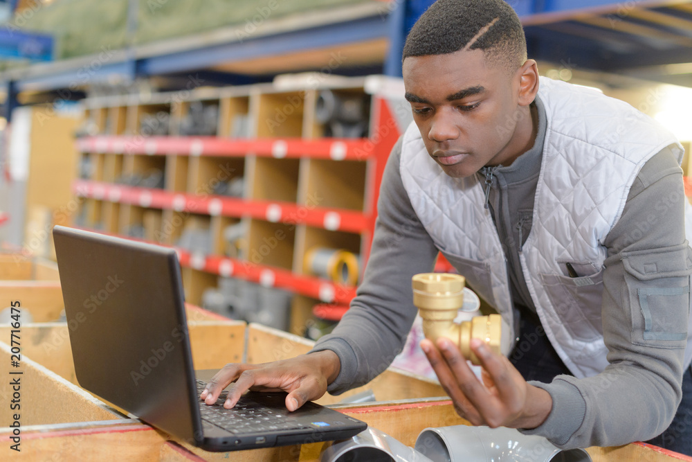 Worker holding pipe fitting and researching on computer Worker holding pipe fitting and researching on computer