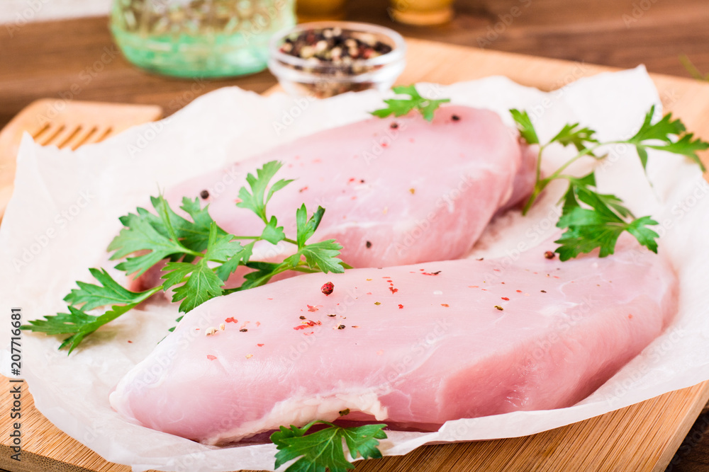 Raw turkey fillet in spices and herbs on a cutting board on a wooden table Raw turkey fillet in spices and herbs on a cutting board on a wooden table