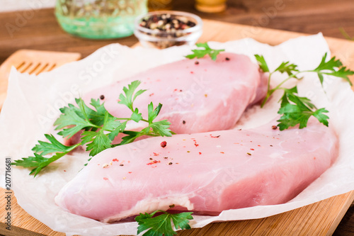 Raw turkey fillet in spices and herbs on a cutting board on a wooden table
