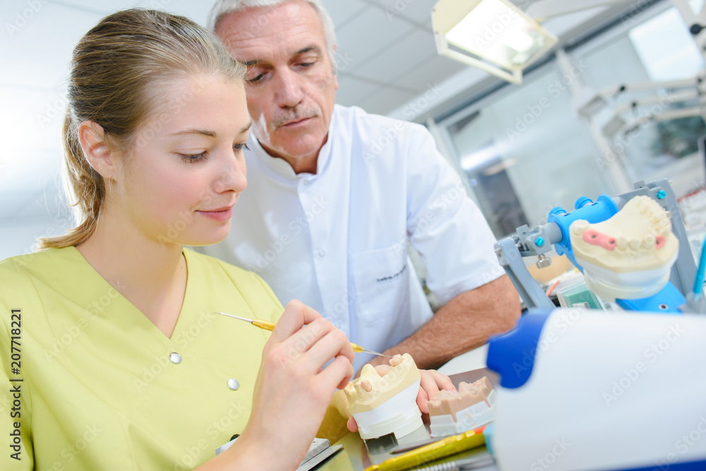 Obraz premium dental technician and supervisor working with tooth dentures